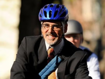 A man in a suit riding a bike.