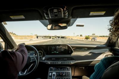 View from the passengers seat of a vehicle with two front passengers on the freeway.