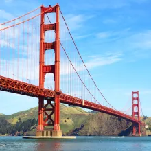 A hero shot from below of the Golden Gate bridge with a beautiful blue sky in the background