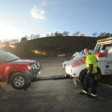 A 511 Freeway Assist towtruck operator hooks up a disabled red SUV