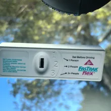 FasTrak tag inside a car windshield, showing a selector switch for the number of people in the car.