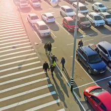 Aerial view of a large parking lot with commuters walking down a crosswalk in the middle