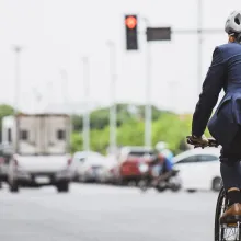 Someone in a suit riding a bicycle in traffic