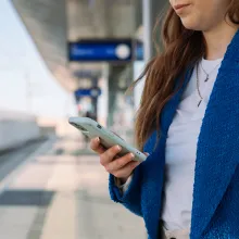 Woman checking her phone while waiting for public transit