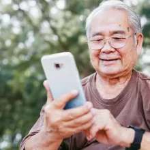A senior man using his phone with a smile