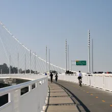 Bicyclists and joggers travel down a dedicated lane along the bay bridge, separate from high-speed traffic.