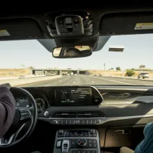 A view out the windshield of a car with two passengers in the front seat, traveling down the highway.