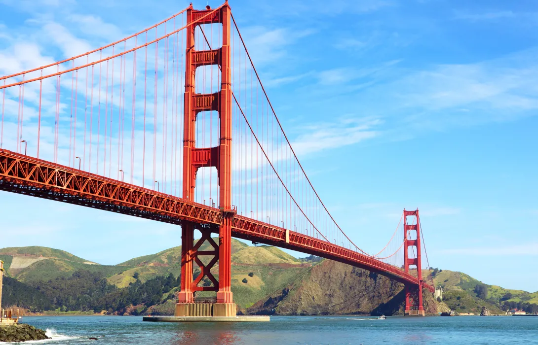 A hero shot from below of the Golden Gate bridge with a beautiful blue sky in the background