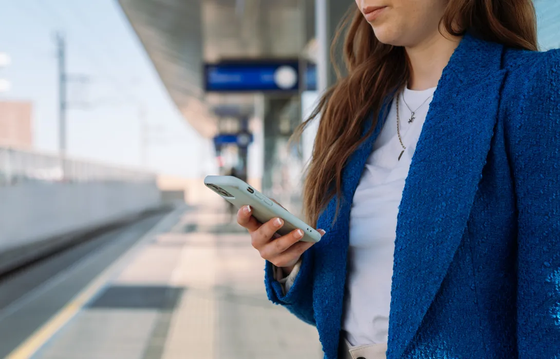 Woman checking her phone while waiting for public transit