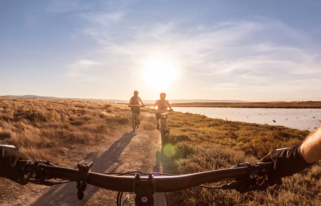 Three people riding bikes into the sunset