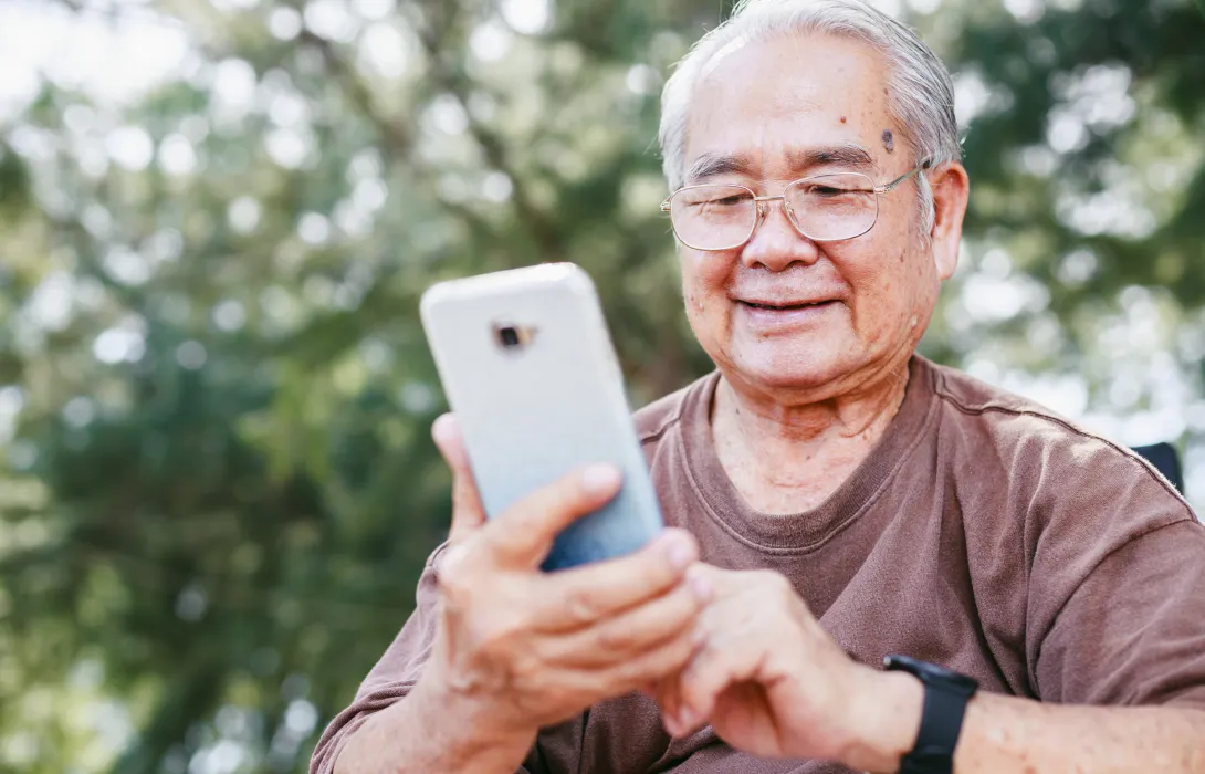 A senior man using his phone with a smile
