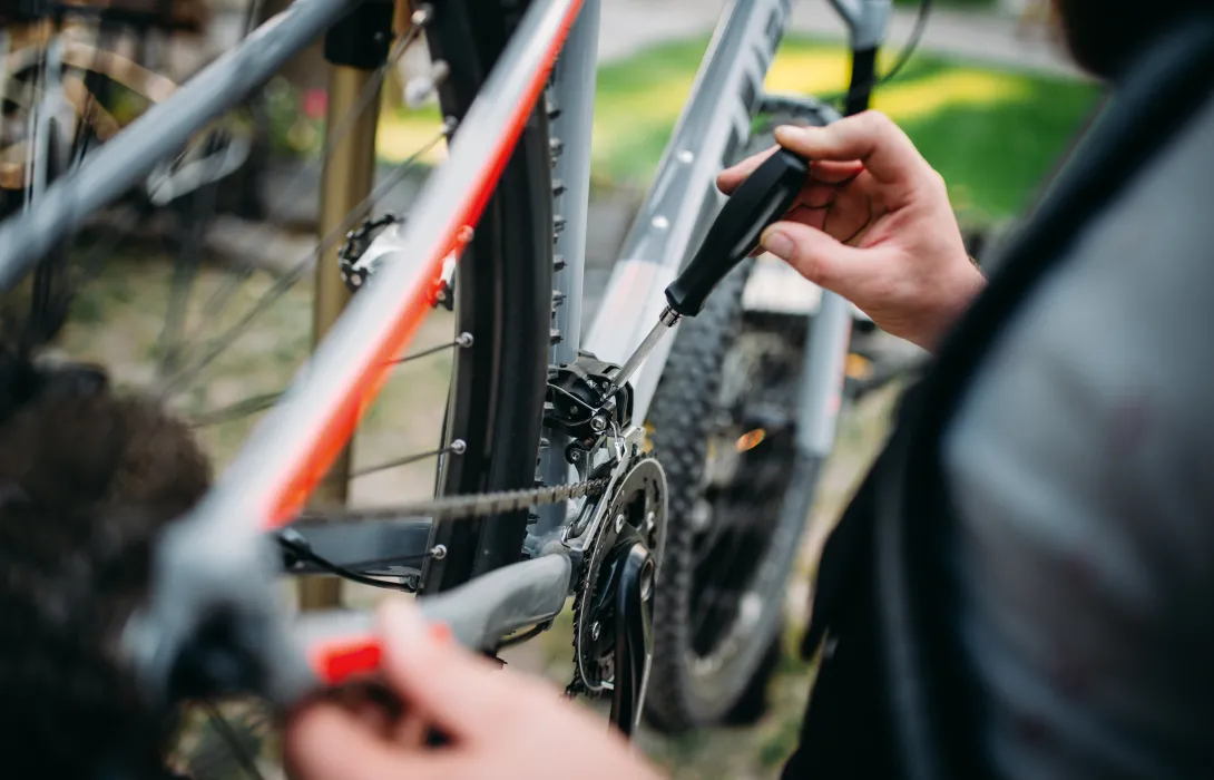 A hand holding a screwdriver fixing a bike.